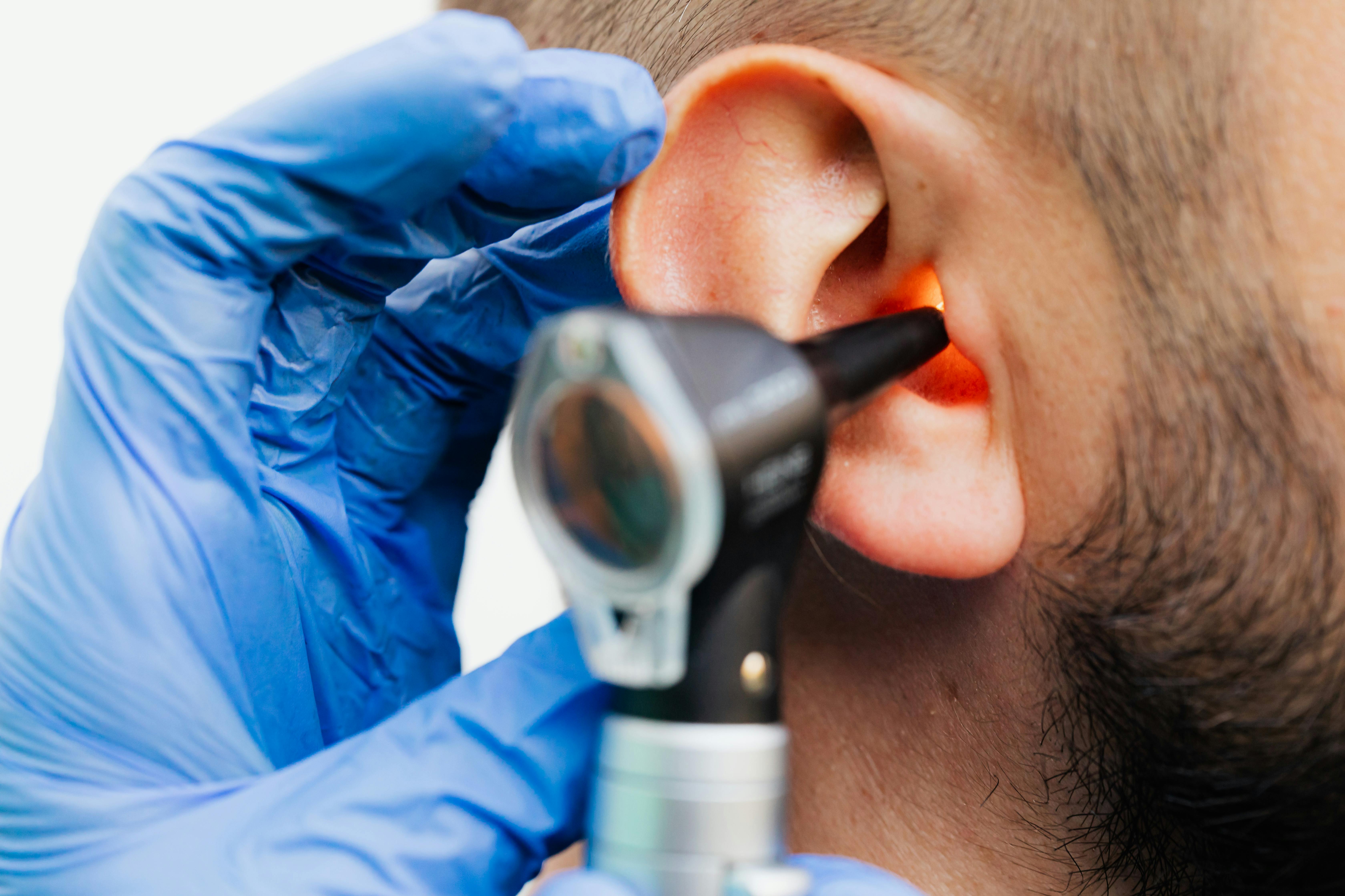 Audiologist examining a patient ear using an otoscope